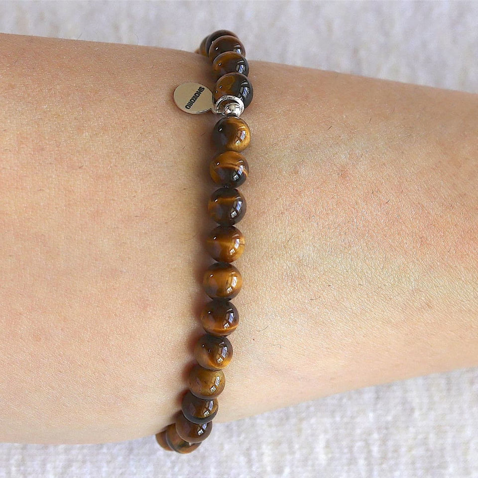 Wearing a natural Tiger Eye bracelet for strength. Minimalist golden brown crystal jewelry for quiet luxury styling. Shokoro.