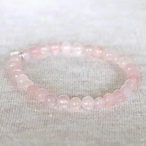 Pink calcite bead bracelet on a light textured surface, with soft pastel tones creating a calm, elegant vibe.