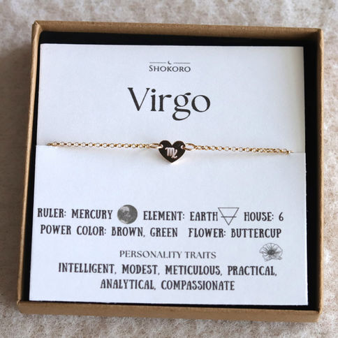 Gold heart anklet with Virgo symbol on card. Text: Ruler: Mercury, Element: Earth, Power Color: Brown, Green, Flower: Butterc