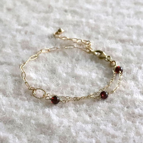 Close-up of 14k gold filled half paperclip half gemstone bracelet in natural red garnet, handcrafted from Shokoro, Toronto.