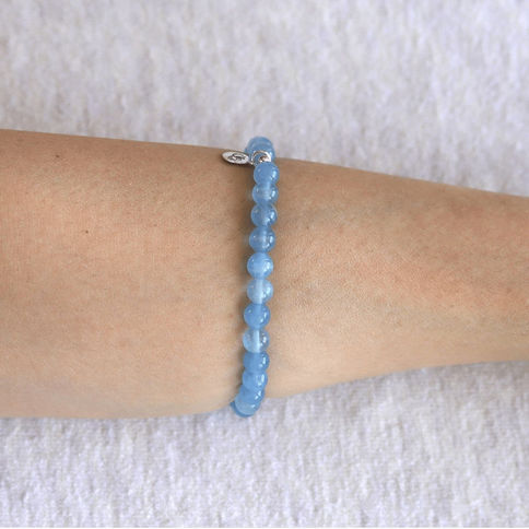 Wearing a 6mm Lemurian Aquatine Blue Calcite bracelet. Minimalist pale blue crystal jewelry for quiet luxury styling. Shokoro