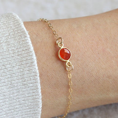 Close-up wearing a natural carnelian bezel bracelet on a dainty chain, artisan minimalist gemstone jewelry for wearing motivation and protection, handmade crystal gift for her birthday.