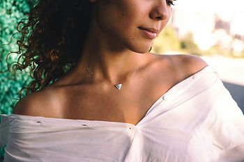 Woman in white off-shoulder shirt, with a triangular necklace, featuring the complete styling guide look with Shokoro Handmade Calcite jewelry