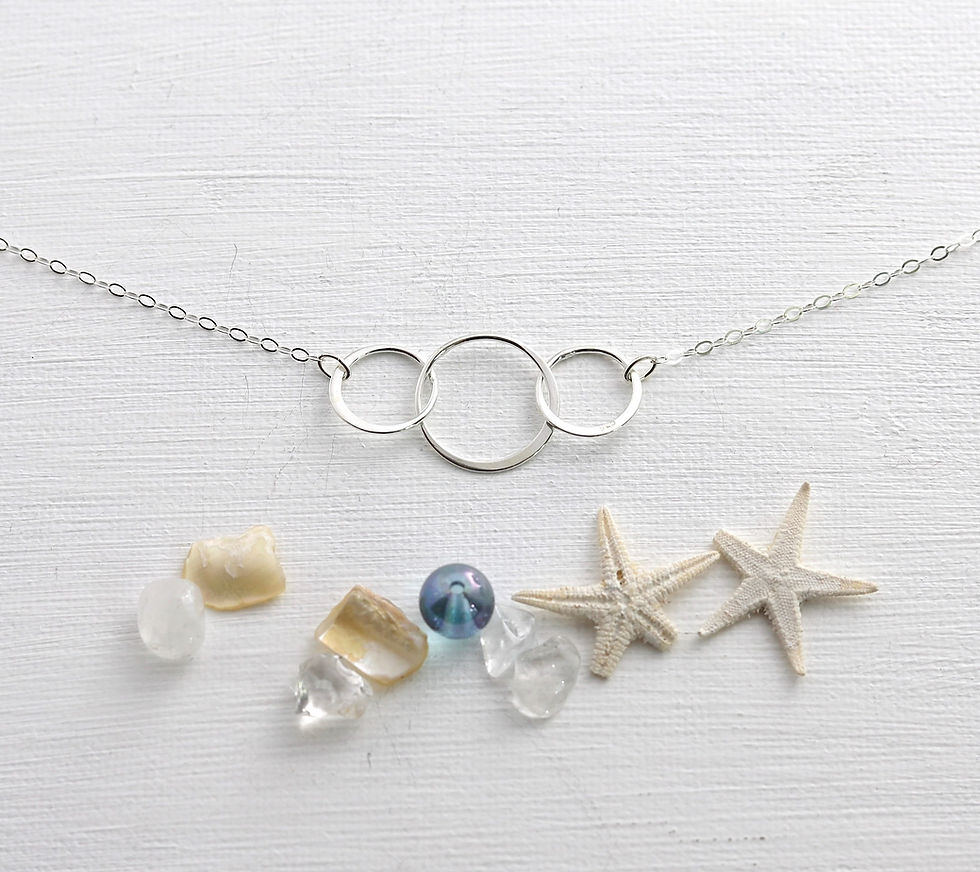 Silver necklace with three interlocking circles on a white surface, Elegant and beautiful minimalist jewelry, Timeless design