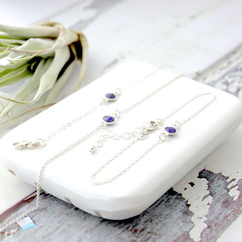 Silver bracelets with purple amethyst crystals on a white surface, Rustic wooden background, bright and elegant setting.