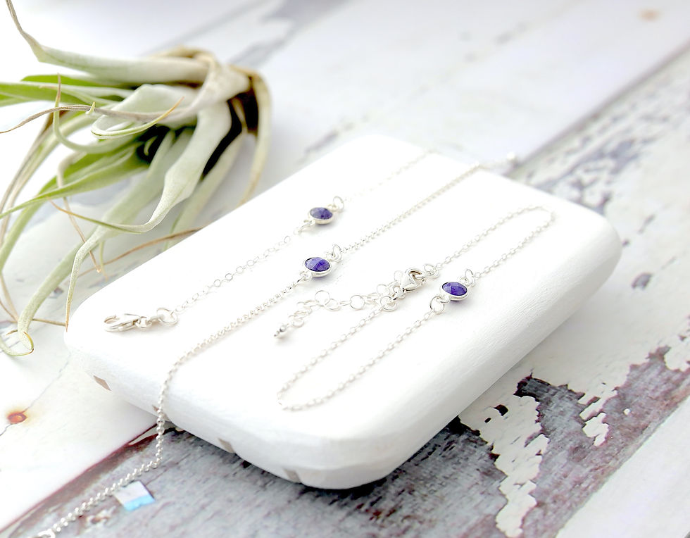 Silver bracelets with purple amethyst crystals on a white surface, Rustic wooden background, bright and elegant setting.