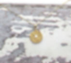 Gold necklace with an evil eye pendant on a rustic white wooden background. The pendant features a central pearl. Amulet jew