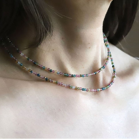 A model wearing a multi-colored rainbow tourmaline beaded necklace in 14k gold-filled layering quiet luxury style.