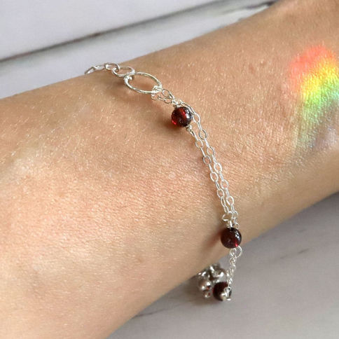 Wearing a delicate Garnet station silver bracelet, subtle quiet luxury design, showcasing craftsmanship details and design.