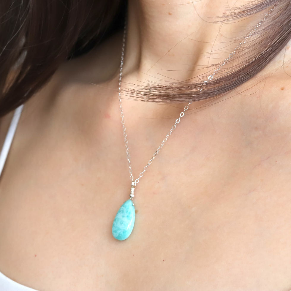 Silver chain necklace with a amazonite teardrop pendant on a woman's neck, set against a soft-focus background. Elegant and s