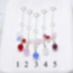 Five rhinestone charms in red, pink, blue, and clear hanging on .925 sterling silver necklace extender chains.