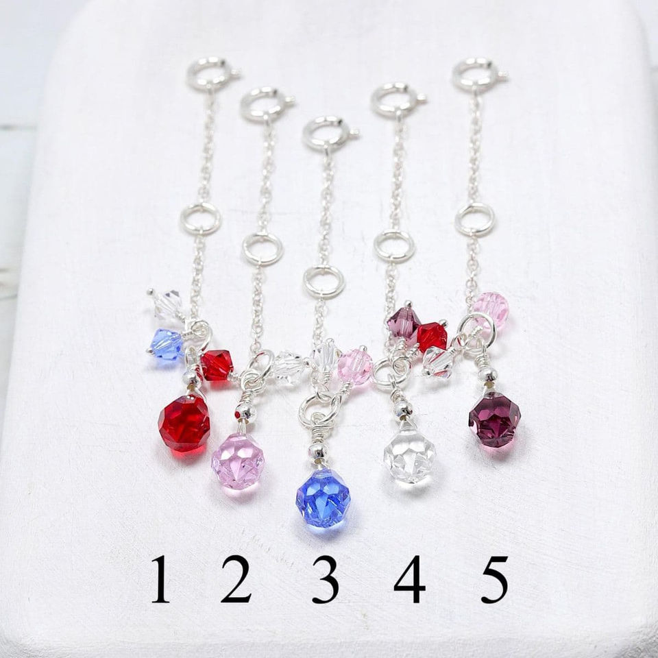 Five rhinestone charms in red, pink, blue, and clear hanging on .925 sterling silver necklace extender chains.
