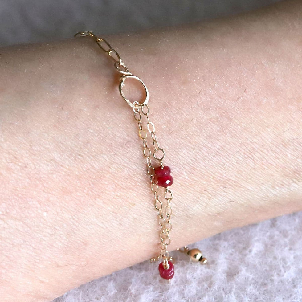 Side view of a 14k gold filled ruby bracelet on a wrist demonstrating the delicate drape and high-quality shine.