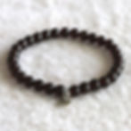 Natural garnet bead bracelet with a lotus charm rests on a white textured fabric, creating a serene and elegant atmosphere.