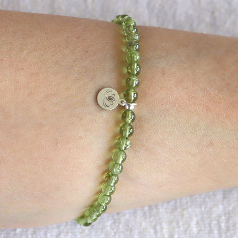 Wearing a dainty 4.5mm Peridot bracelet. Minimalist lime green birthstone jewelry for a subtle glow. Shokoro.