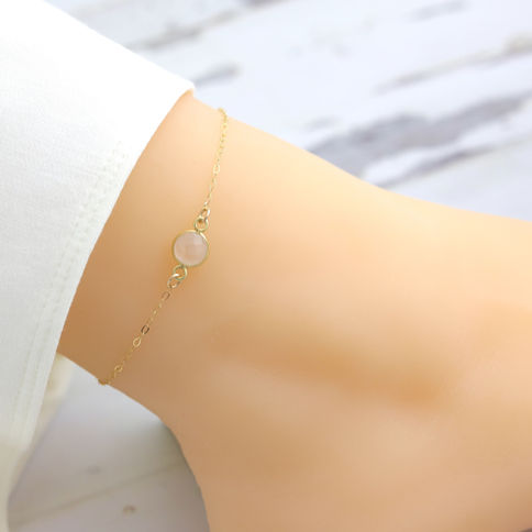 Close-up worn natural rose quartz anklet, delicate 14k gold filled crystal jewelry, Feminine and elegant mood.
