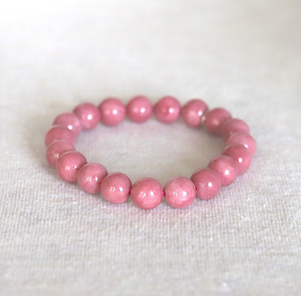Pink rhodonite beaded bracelet on a light textured surface, showcasing glossy, round beads in a circular arrangement.