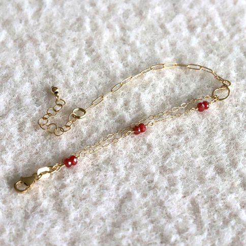Natural ruby bracelet displayed in an elegant arch highlighting the custom hand-hammered figure-8 wire connector.