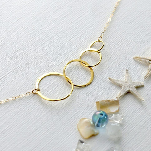Angled view of a high quality, gold four circle pendant to illustrate the high-clarity metal and minimalist artisan design.