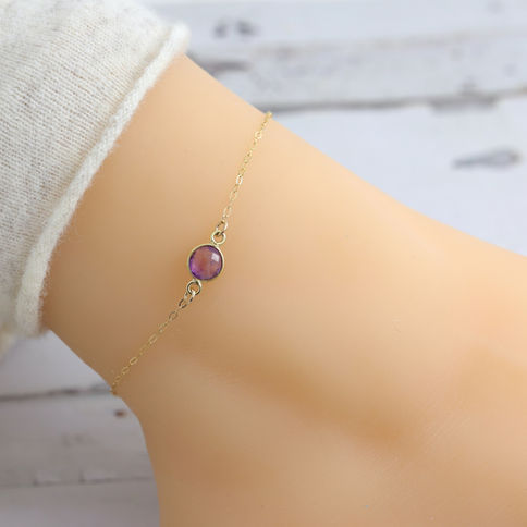 Delicate 14k gold chain bracelet with purple amethyst gemstone on wrist, set against a soft, Elegant and feminine jewelry.