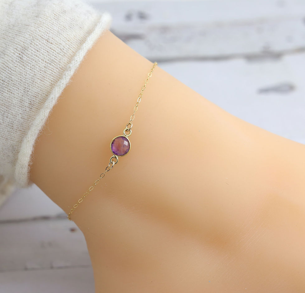 Delicate 14k gold chain bracelet with purple amethyst gemstone on wrist, set against a soft, Elegant and feminine jewelry.