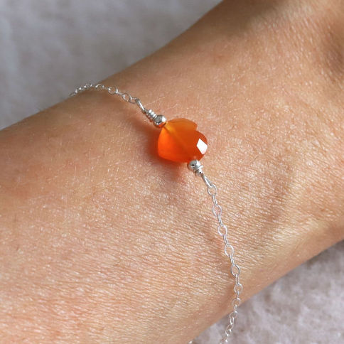 Close-up, wearing a dainty sterling silver with sparkling Carnelian heart, handmade chain bracelet and natural gemstone,