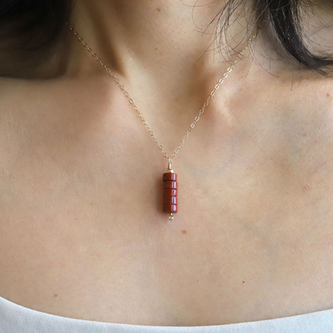 Wearing a Red Jasper bar necklace in vertical style. Dainty 14k Gold Filled gemstone jewelry for grounded strength.