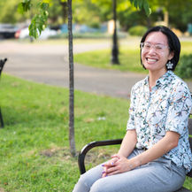A girl smiles at the camera while sitting on a bench.