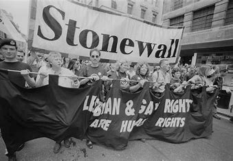 Marchers holding up banners that say "stonewall" and "Lesbian & Gay Rights are Human Rights!"