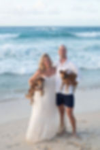A couple holds their dogs and smiles on the beach with a blue sea in the background. Photographed by Tofino photographer Kaitlyn Shea.