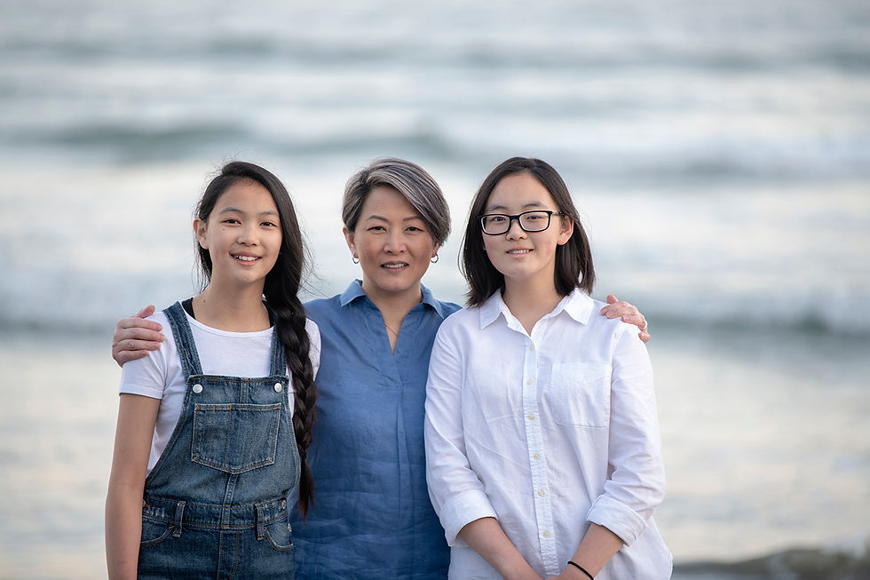 Mom stands with her daughters on the beach during their family pictures in Tofino | Photographed by Kaitlyn Shea