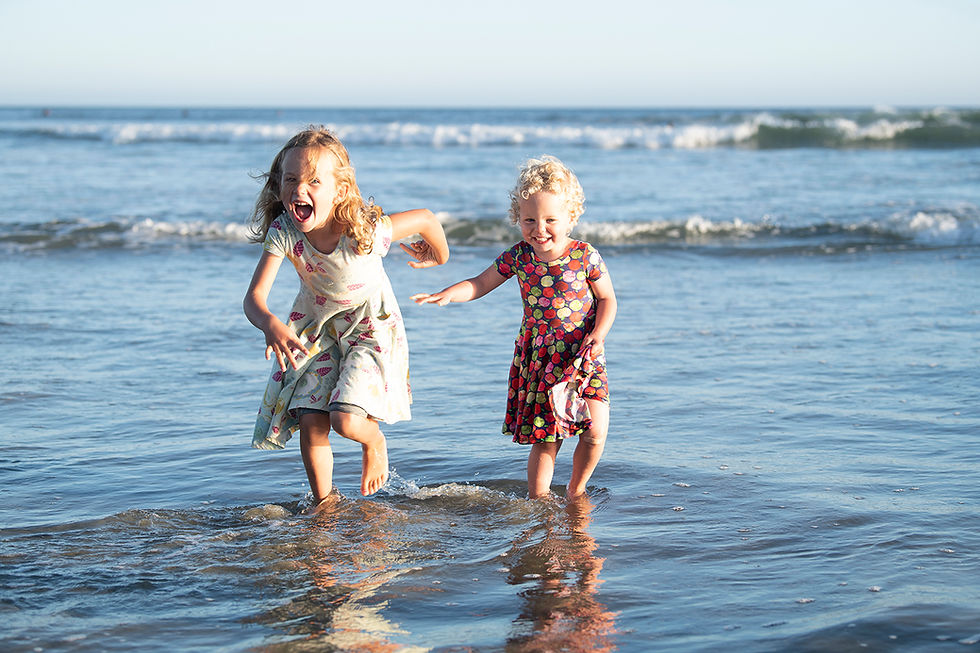 Sisters run through the water during Tofino family photos. Photographed by Kaitlyn Shea.