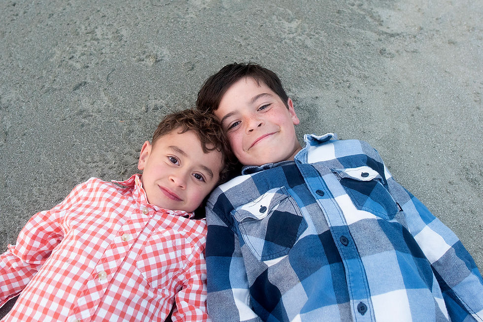 Brothers lay on the beach together during a family photo shoot in Tofino. Photographed by Kaitlyn Shea.