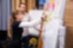 Das Foto zeigt zwei Personen vor einen Whiteboard, wie sie verschieden farbige Klebezettel entlang einer Linie kleben