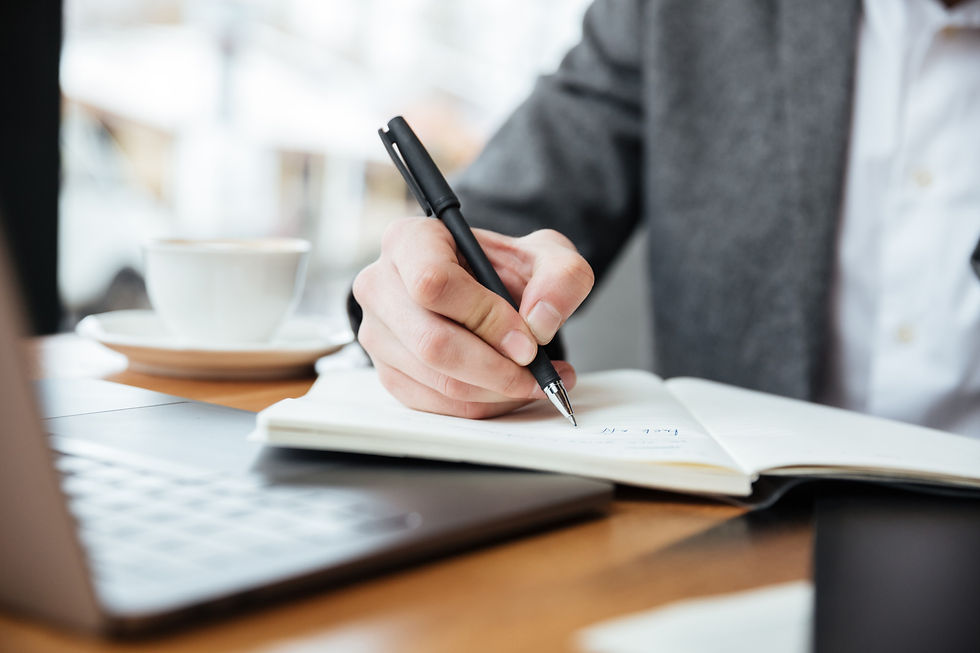 cropped-image-of-businessman-sitting-by-the-table-in-cafe-with-laptop-computer-and-writing