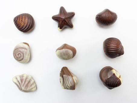 Box of chocolate seashells on white background, a common trigger food for emotional eating and overeating.