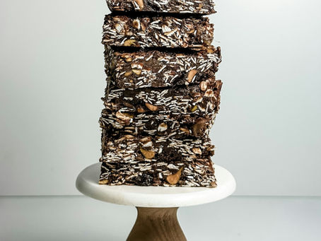 “Stack of five chocolate-caramel cereal bars on a small pedestal stand, photographed in natural light against a white background. Perfect example of a fun-sized snack that can trigger emotional eating or overeating, even when you’re not hungry.”