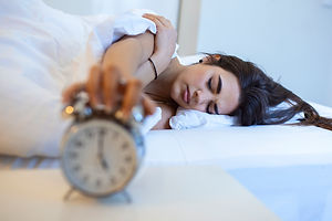 woman-lying-in-bed-turning-off-an-alarm-clock-in-the-morning-at-5am-hand-turns-off-the-ala