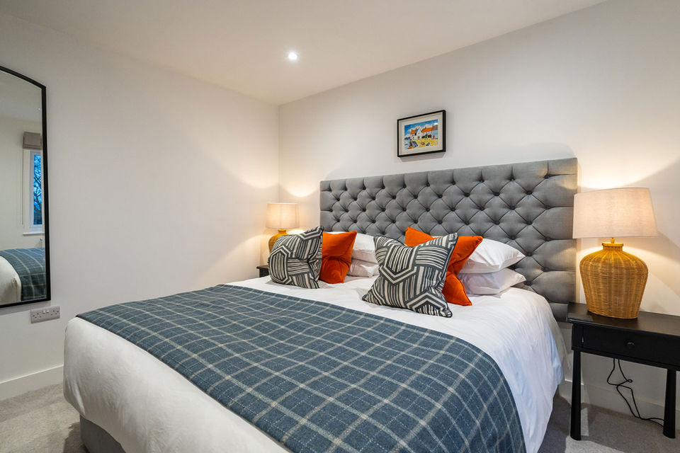 Treloyhan bedroom with large fabric headboard and orange cushions