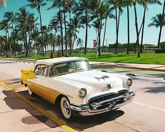Voiture ancienne décapotable bleu clair circulant sur Ocean Drive devant les hôtels Art Deco, lors d'une visite avec Visite de Miami LLC.
