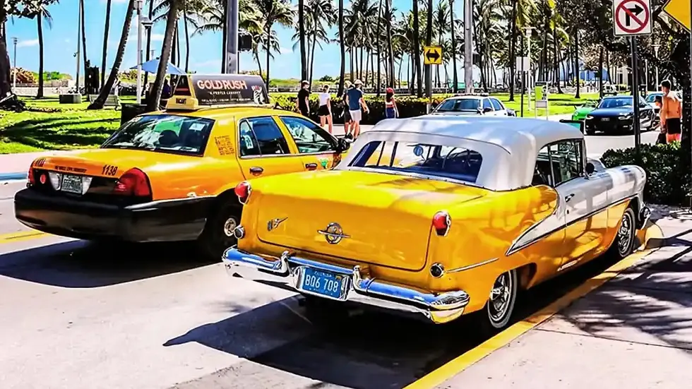 Une voiture jaune et blanche de style rétro garée, vue de l'arrière, avec une autre voiture jaune visible à côté.