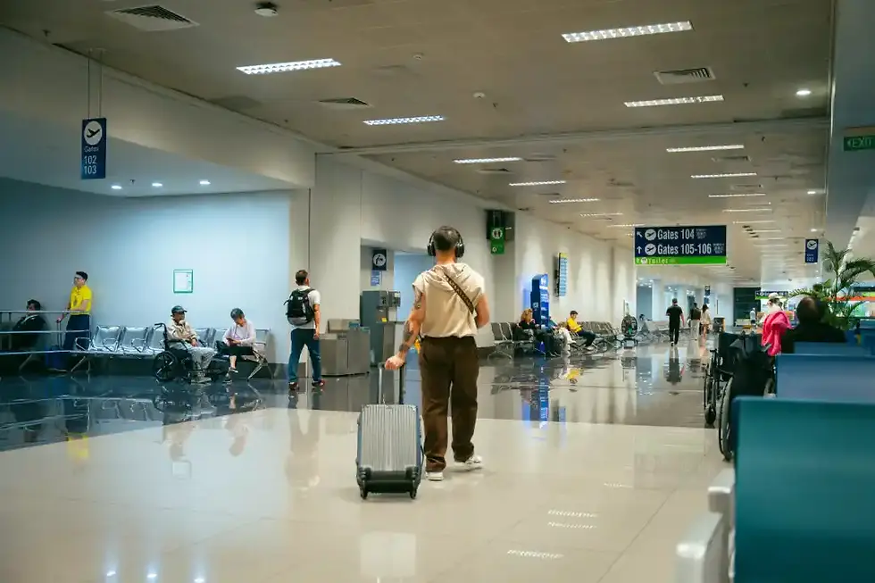 Un homme marche dans un couloir de l'aéroport de Miami en tirant sa valise.