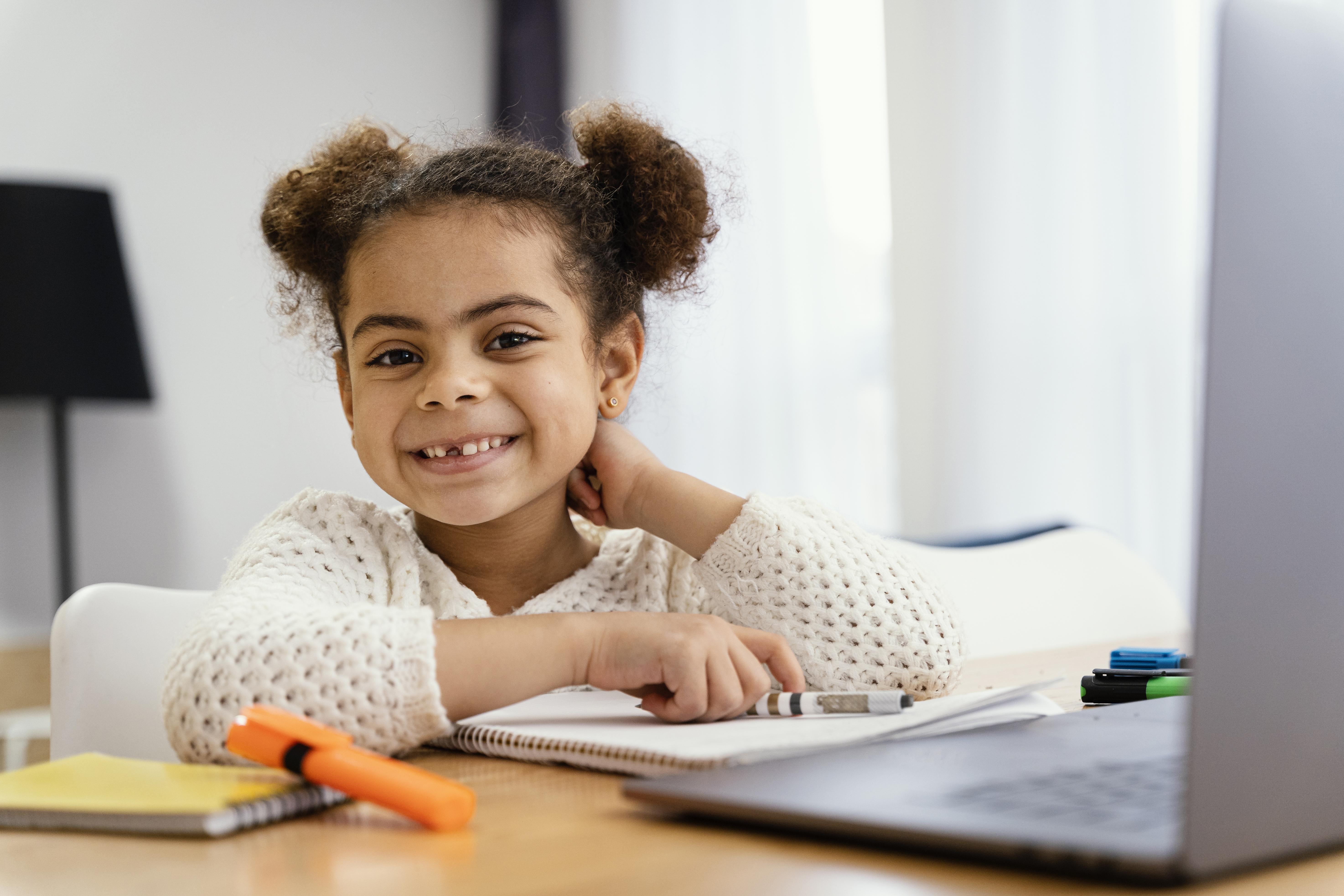 front-view-smiley-little-girl-home-online-school-with-laptop.jpg