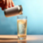 pouring blank can beverage into a glass and the fluid is sparkling opaque liquid but mostl