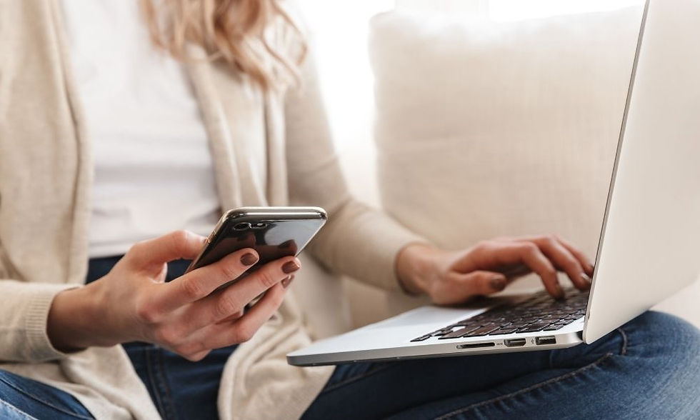 Business owner checking transactions between phone and laptop