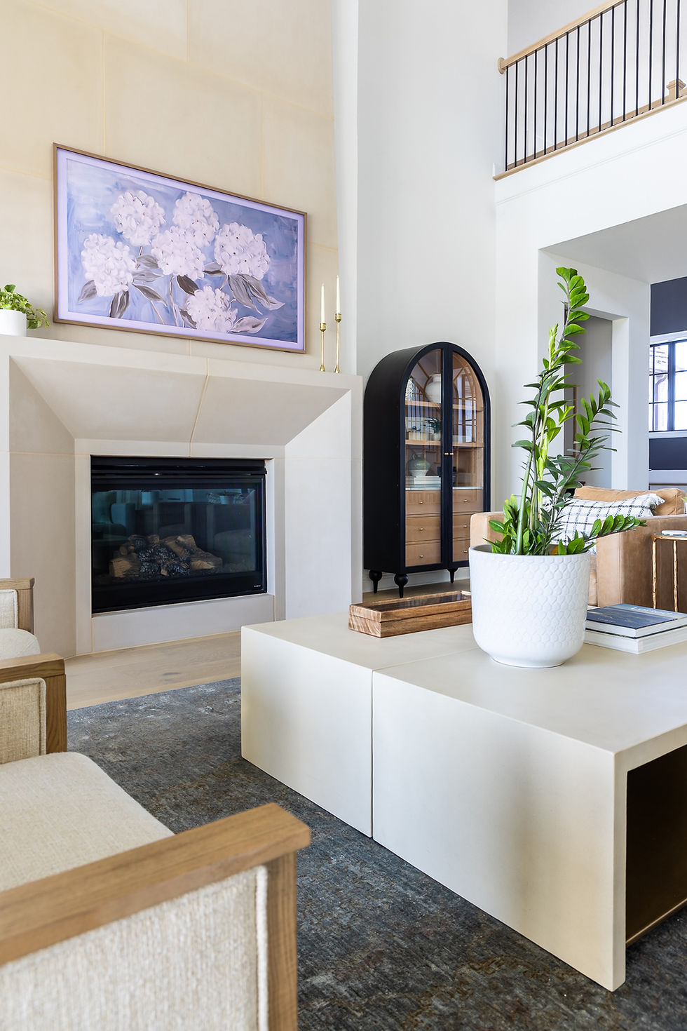 A lightly styled family room with large cast stone fireplace, arched cabinet, and coffee table; an example for staging your home to sell