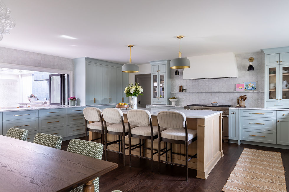 Elegant kitchen with pastel blue cabinets, marble island, striped chairs, pendant lights, and flowers. Bright, inviting atmosphere.