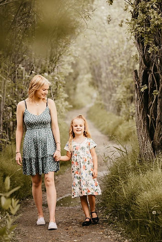 sisters walking through a green forest trail smiling