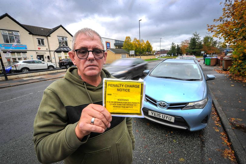 Gary Fox with the parking ticket he received while helping a blind man customer (Image: Vincent Cole - Manchester Evening News)