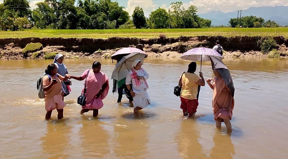 Sisters in India crossing a flooded river as they go about their work.